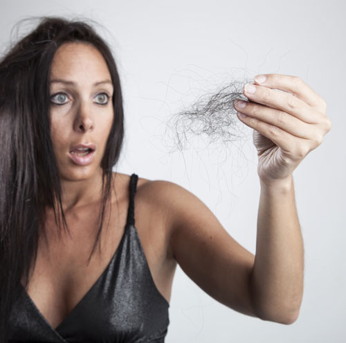 woman looking at clump of hair in distress